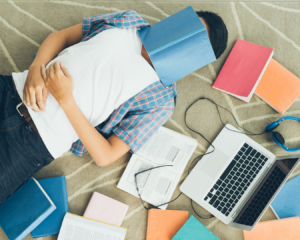 chico dormido entres sus libros y computadora