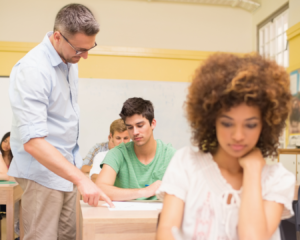 Profesor revisando trabajo de un estudiante en el aula