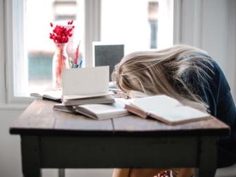 persona dormida sobre libros en la mesa